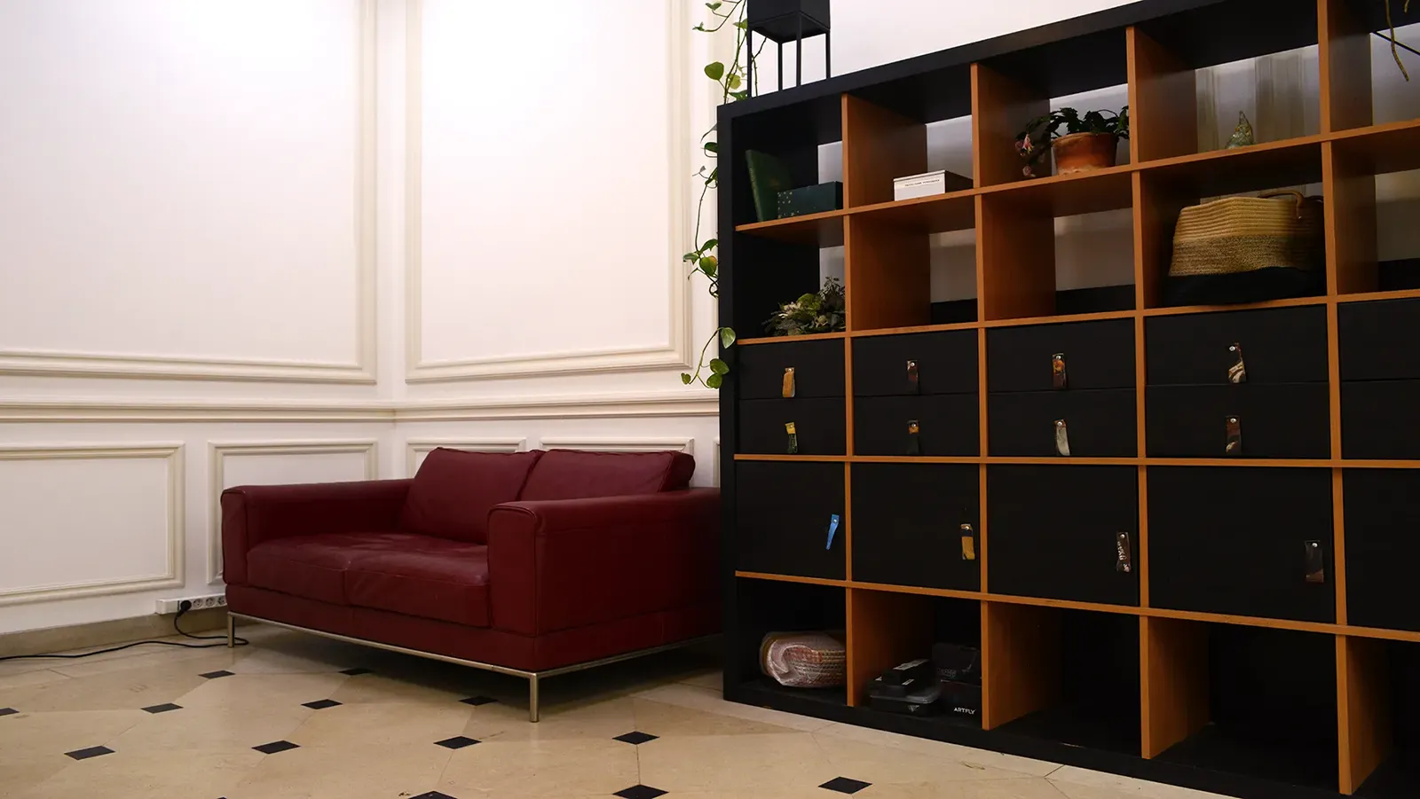 Espace détente avec canapé rouge et étagère à casiers dans un intérieur lumineux.