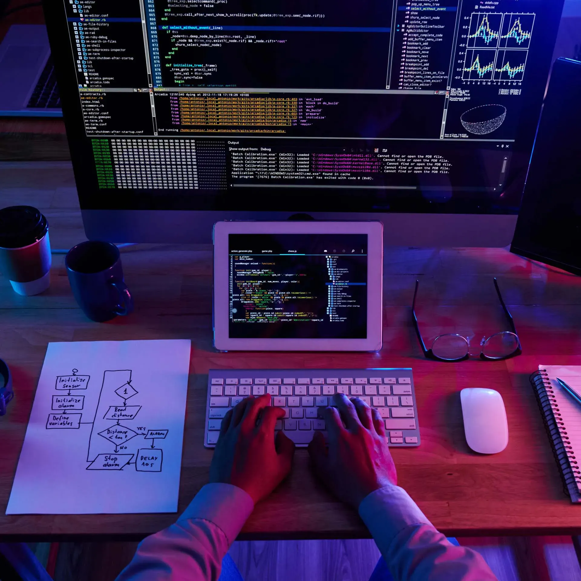 Game programmer développant le code d’un jeu vidéo sur plusieurs écrans.