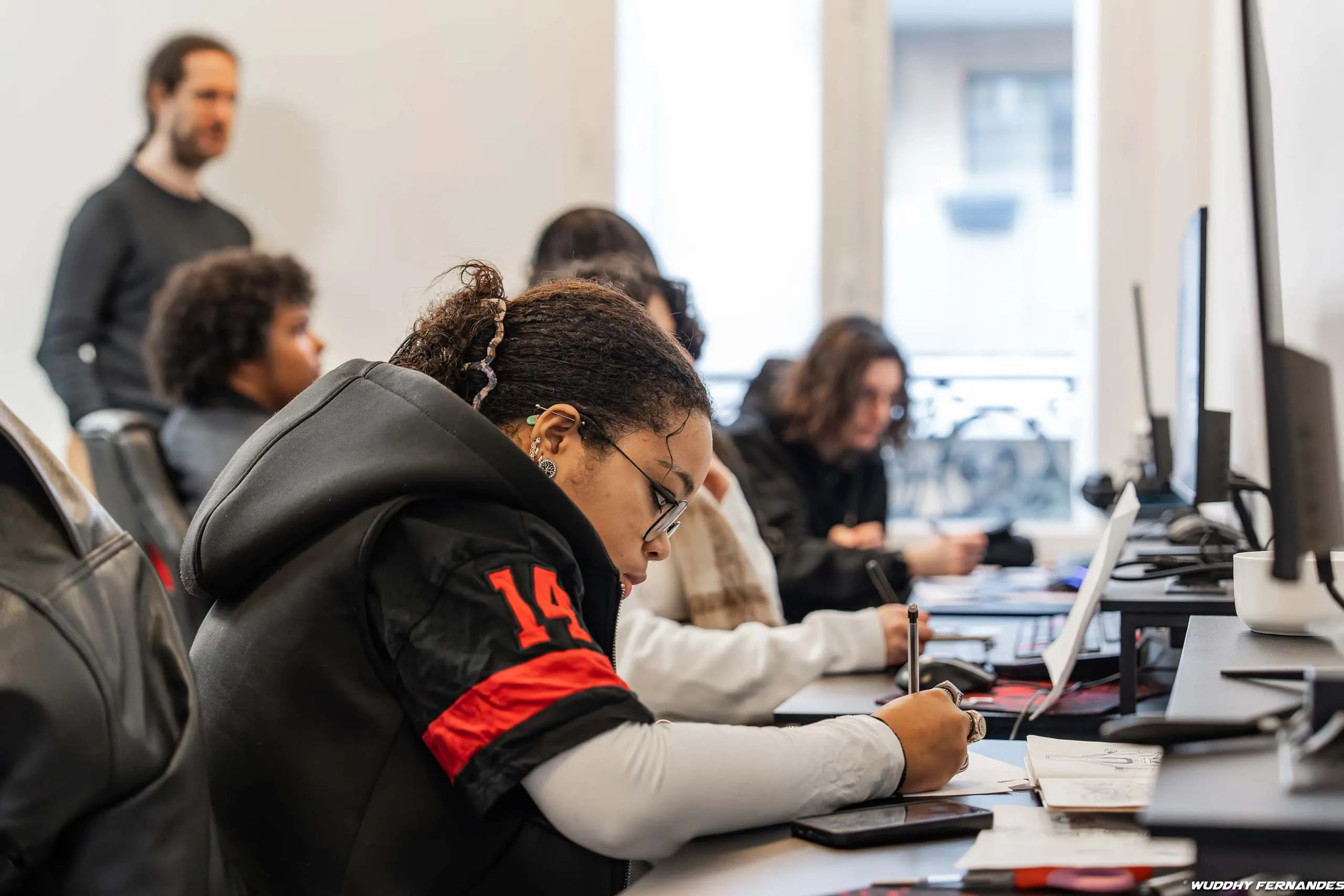 Étudiants travaillant dans une salle de formation informatique pendant qu’un formateur supervise le groupe.