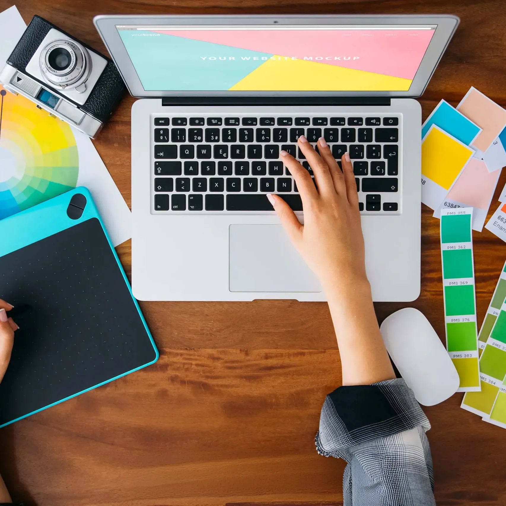 Graphiste en train de concevoir un design sur ordinateur avec palette de couleurs et tablette graphique.