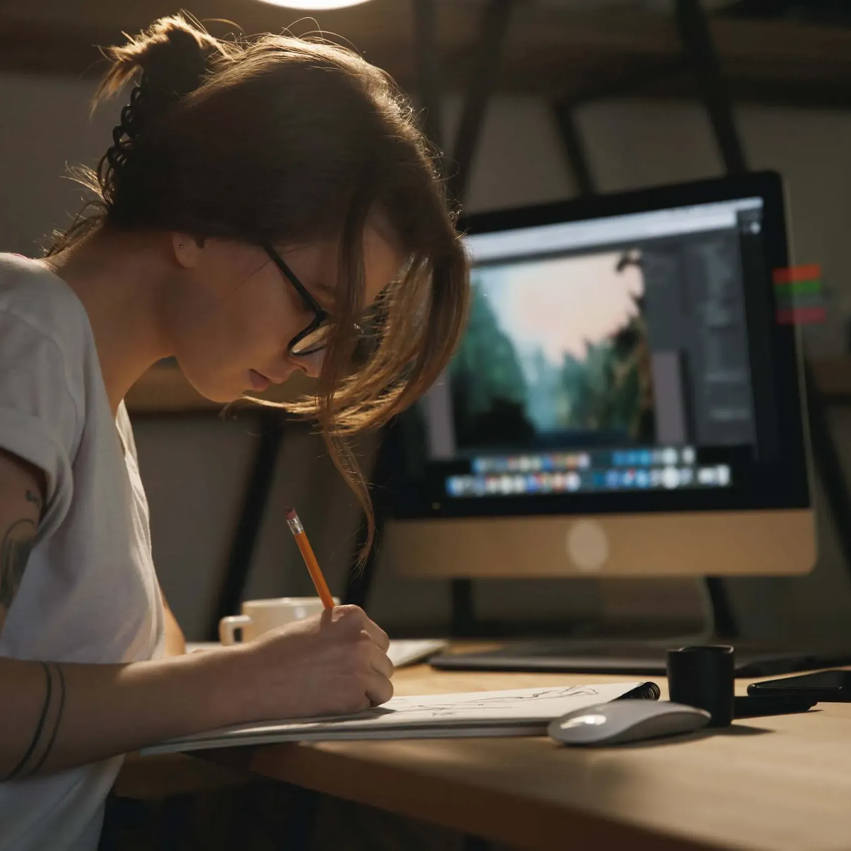 Illustratrice travaillant sur un croquis à son bureau avec un ordinateur affichant une image.