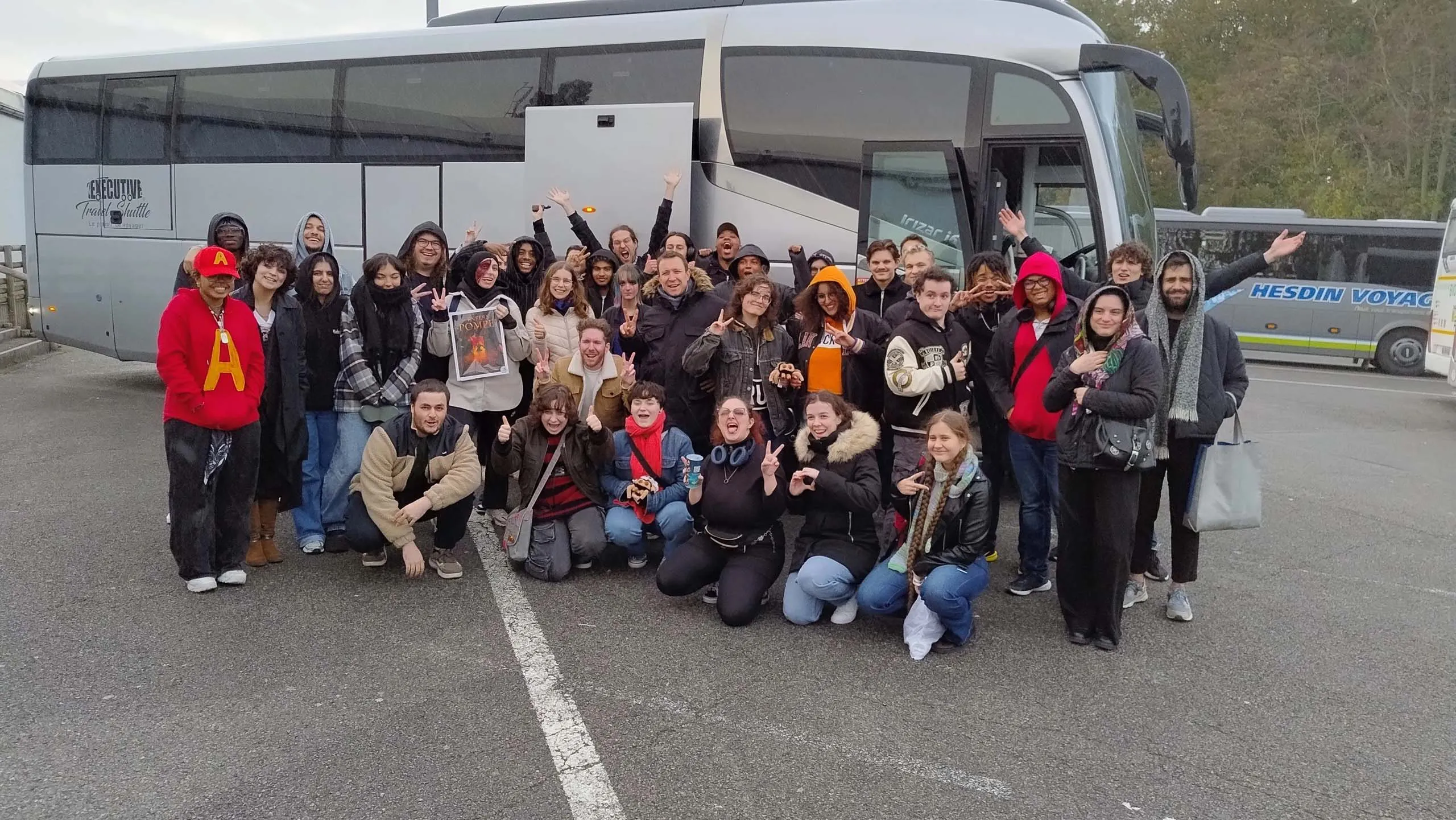 Groupe d'étudiants posant devant un bus lors d'une sortie scolaire